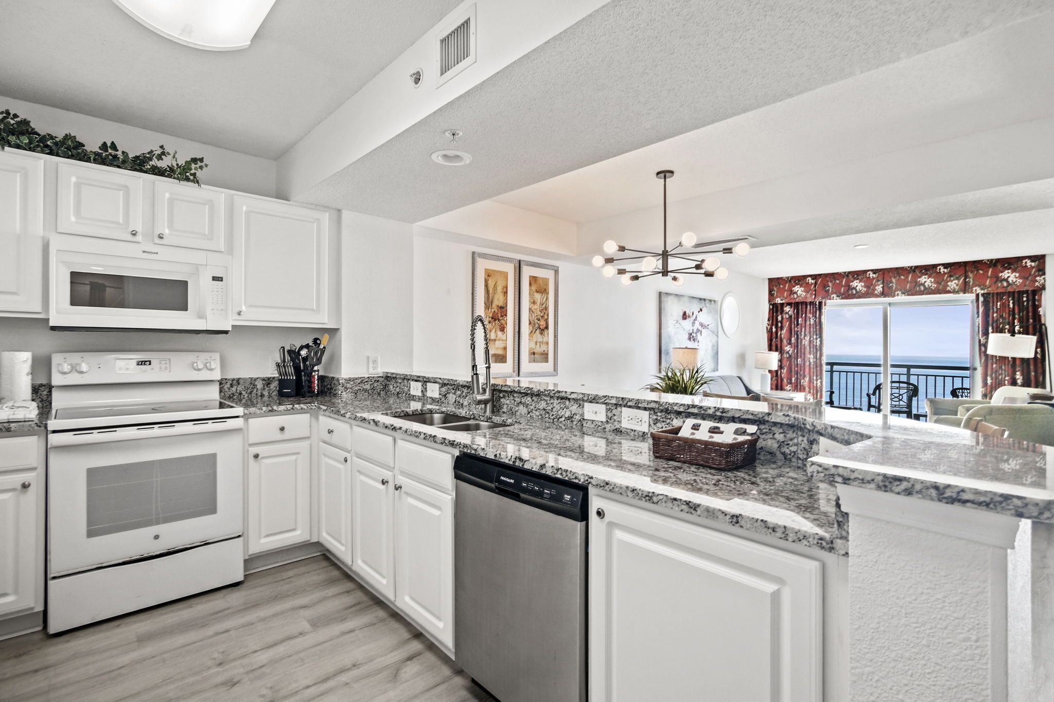 A modern kitchen with white cabinetry, a built-in oven, microwave, and dishwasher.