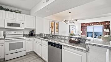 A modern kitchen with white cabinetry, a built-in oven, microwave, and dishwasher.