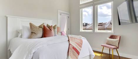 Un dormitorio con una cama, una silla y una ventana con persianas.