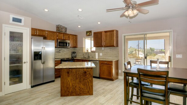 A modern kitchen with wooden cabinets, stainless steel appliances, and a large island. - Beautiful home with 2 masters! (Lake Havasu City)