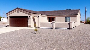 A single-story house with a garage, a small front yard, and a clear blue sky. - Beautiful home with 2 masters! (Lake Havasu City)