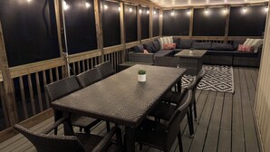 A covered outdoor patio with a dining table and chairs, a sofa, and a patterned rug. - Steps from beach access, family friendly home with all the amenities! (Milton)