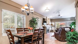 A dining area with a wooden table and chairs, a chandelier, and a large window with blinds. - Little taste of Heaven, 5 min walk to pool/hot tub, close to hikes & restaurants (Sedona)
