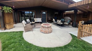 Un patio techado con mobiliario exterior, una chimenea y una valla de madera.