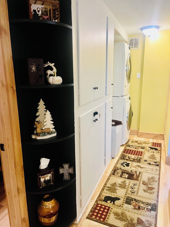 A hallway with a black shelf unit displaying various decorative items, white cabinets, and a patterned rug.