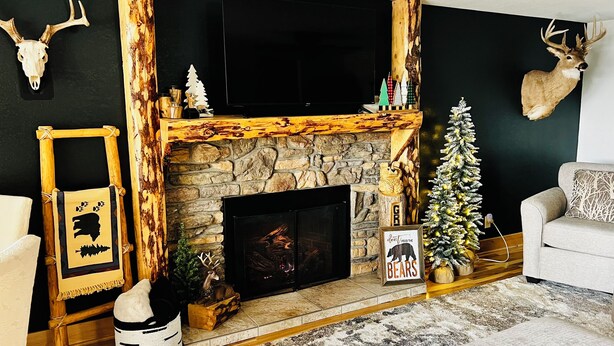 Una sala de estar acogedora con una chimenea de piedra, una cabeza de venado montada y un árbol de Navidad.