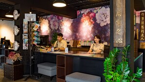A reception area with a floral mural, clocks, and a desk with two staff members. - 22alleys (Magong)