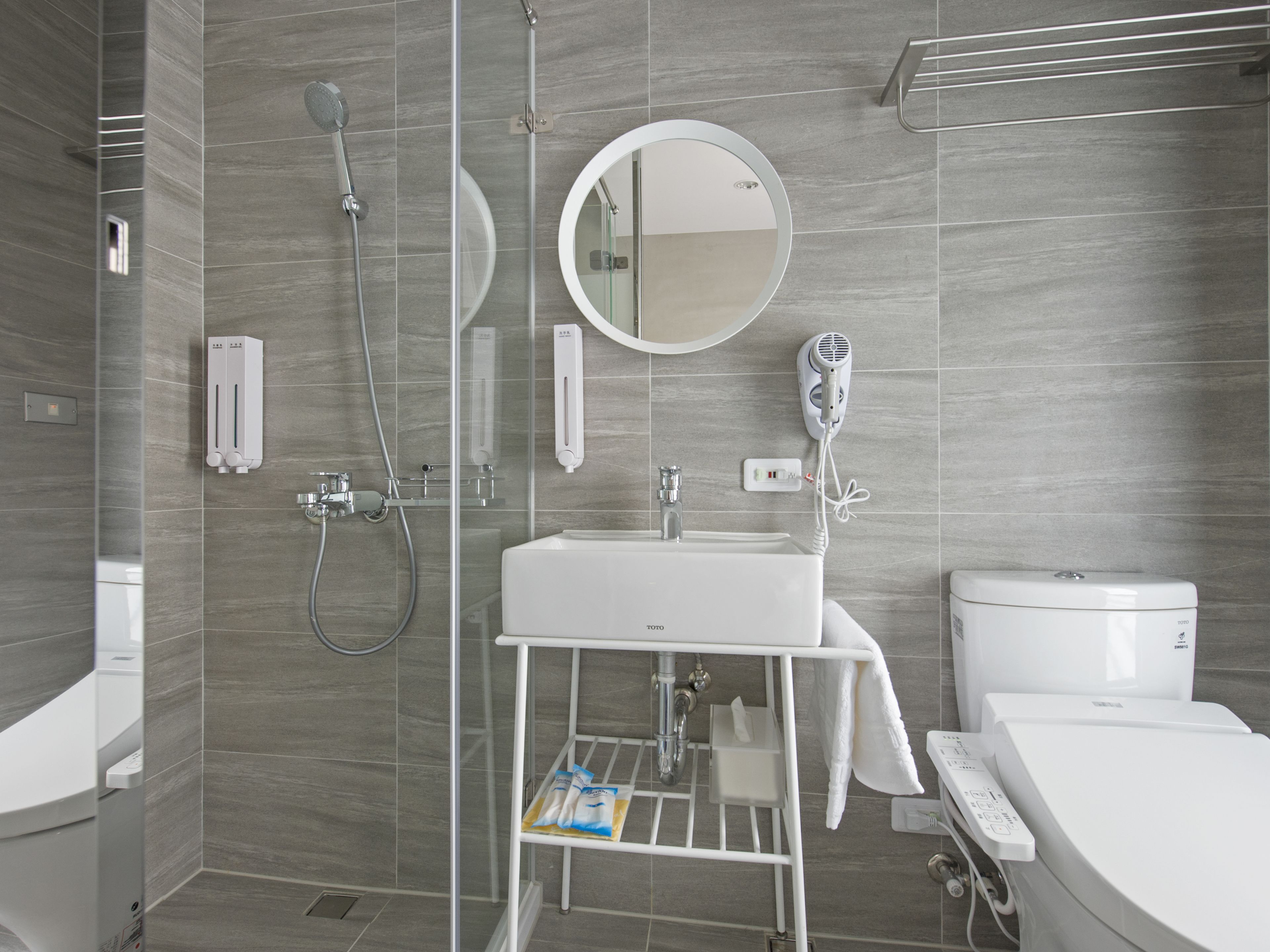 Een moderne badkamer met een douchecabine van glas, een witte wastafel en een toilet.