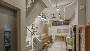 Una cocina moderna con una isla central, taburetes de bar, un refrigerador y una escalera que lleva a un nivel superior.