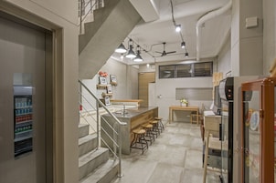 Una cocina moderna con una isla central, taburetes de bar, un refrigerador y una escalera que lleva a un nivel superior.