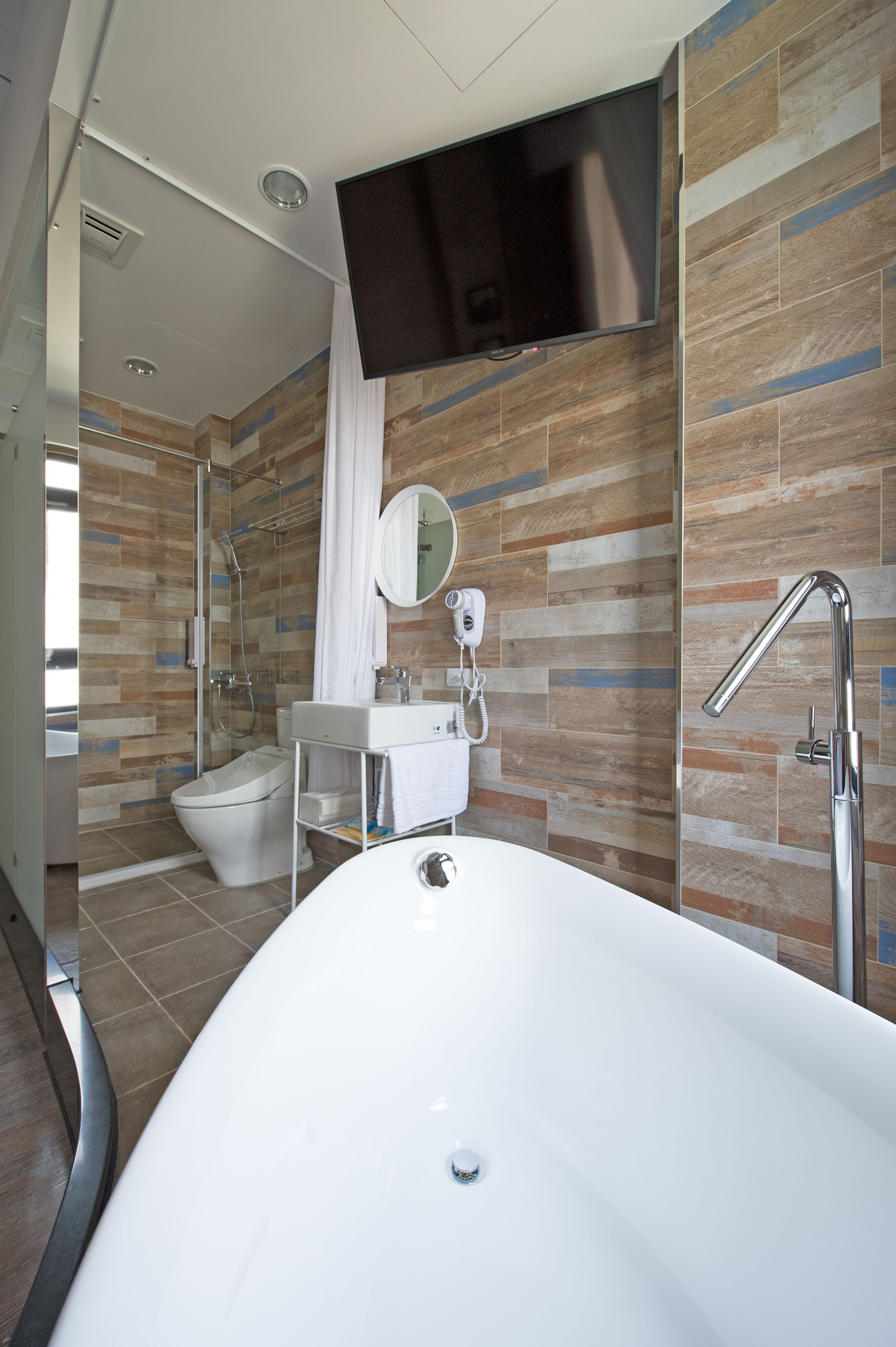 A modern bathroom with a freestanding bathtub, a glass-enclosed shower, a toilet, and a vanity with a mirror.