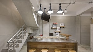 Una cocina moderna con una isla central, taburetes de bar, un lavamanos de acero inoxidable y una escalera.