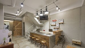 Una cocina moderna con una isla central, taburetes de bar, una escalera de madera y un televisor de pantalla plana montado en la pared.