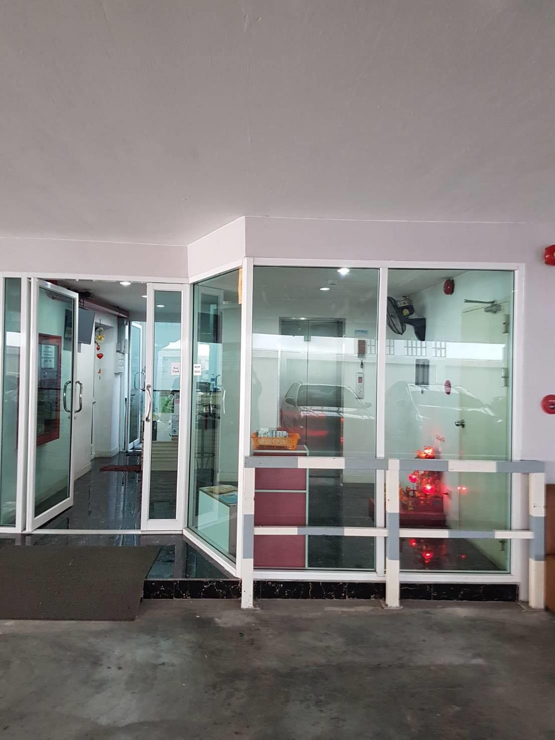 A modern interior with glass partitions, a visible car, and a red emergency button on the wall.