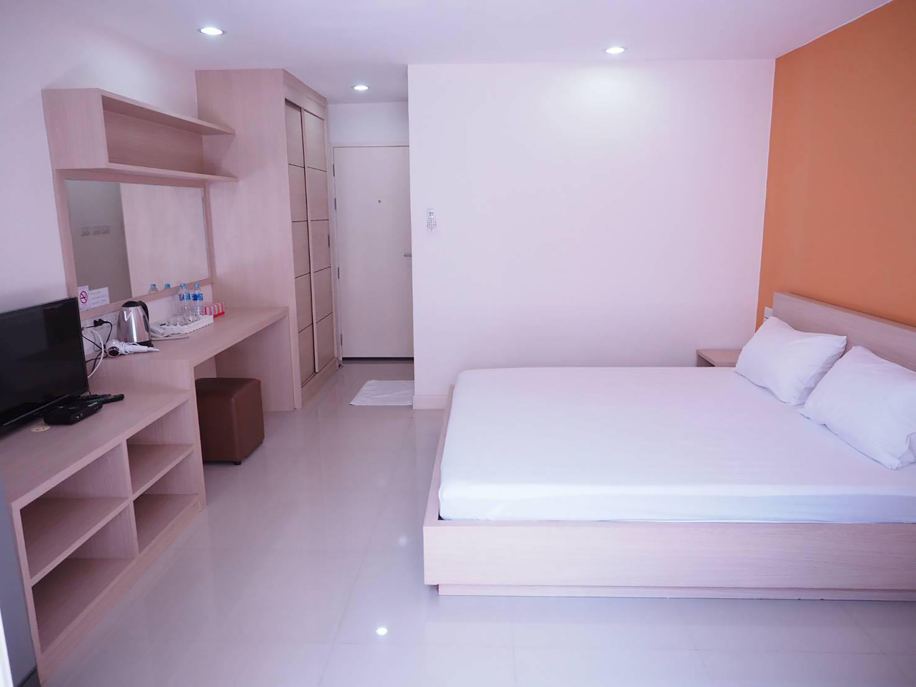 Ein modernes Hotelzimmer mit einem großen Bett, einem Schreibtisch mit Computer und einem Kleiderschrank.