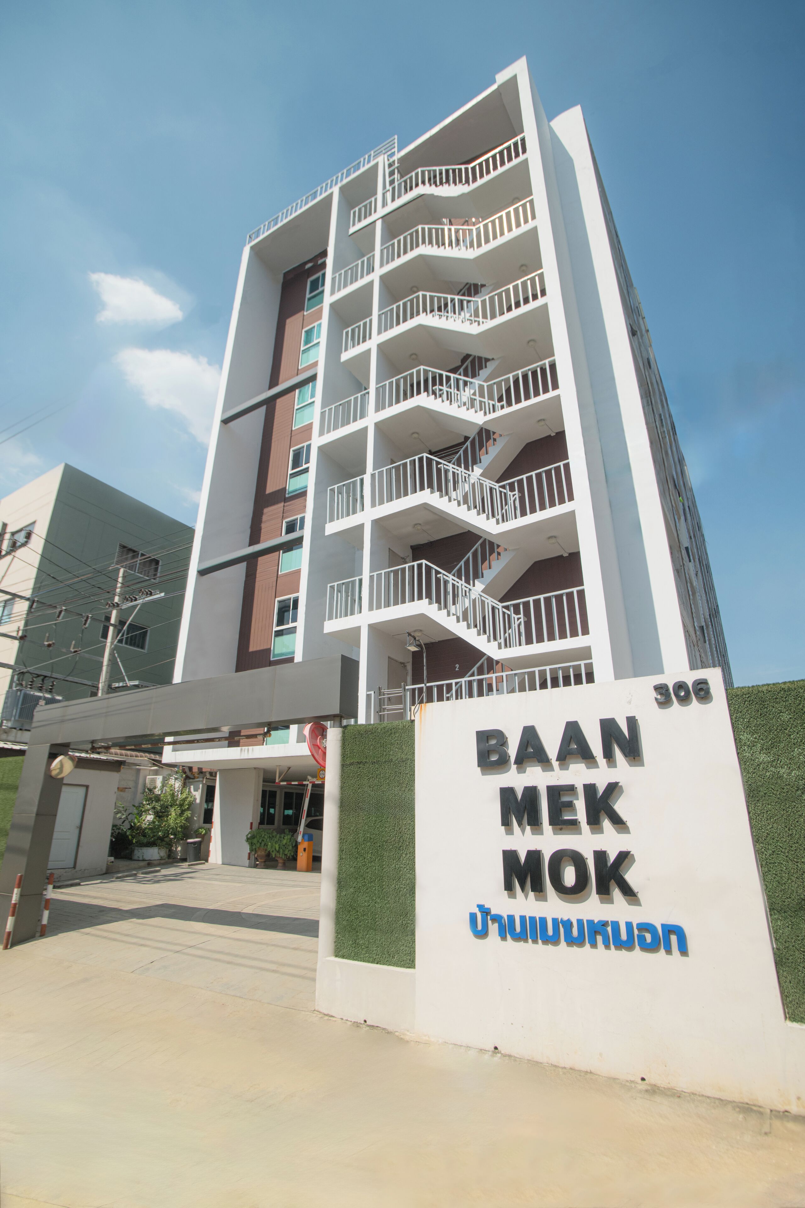 Un bâtiment moderne à plusieurs étages, sur lequel on peut lire l’inscription « BAAN MEK MOK » ainsi que des caractères de l’alphabet thaï.