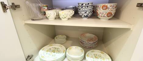 A storage area with shelves holding stacks of plates and bowls.