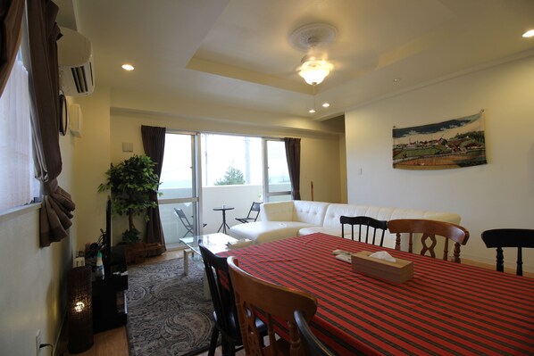 A dining area with a table set for four, a sofa, and a window with curtains.