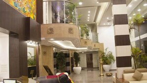 Eine moderne Lobby mit einer Rezeption, einer großen Elefantenstatue und einer Sitzecke mit einer Couch und Sesseln.