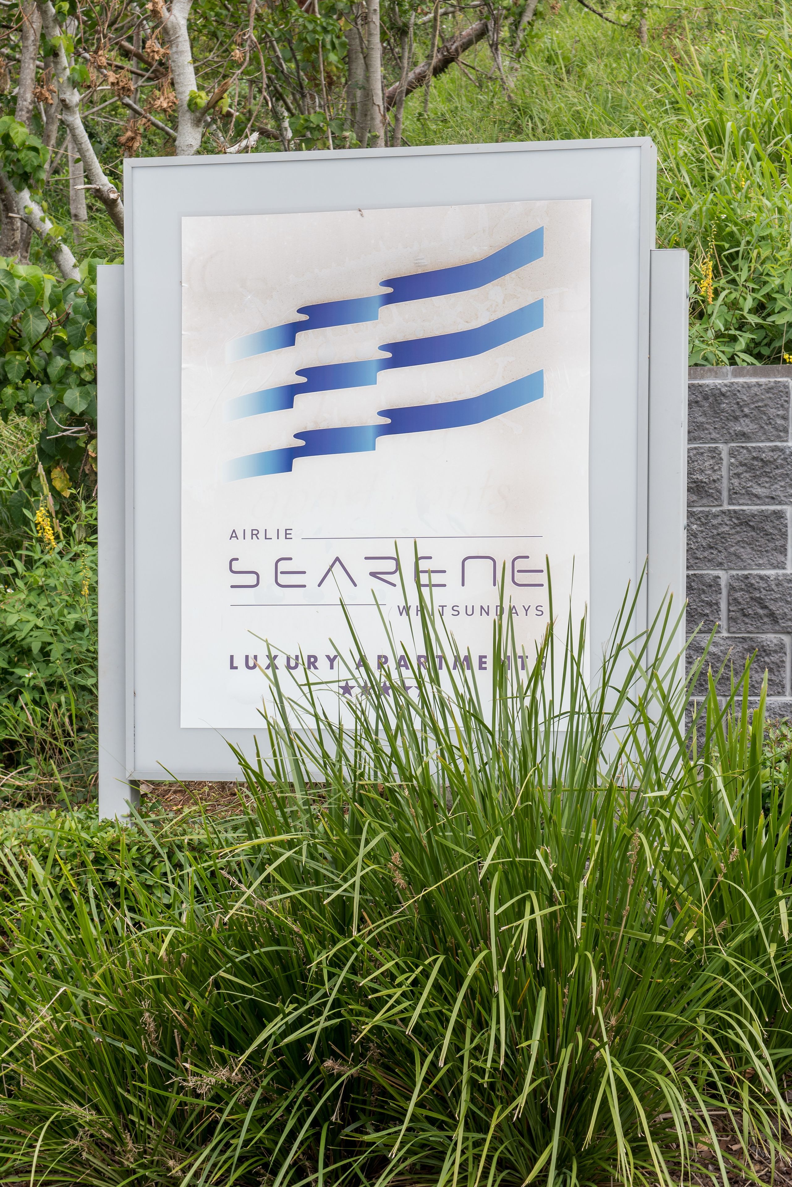 Une enseigne pour les « appartements de luxe Airlie Seareen », avec un design moderne et une vue sur une végétation luxuriante.