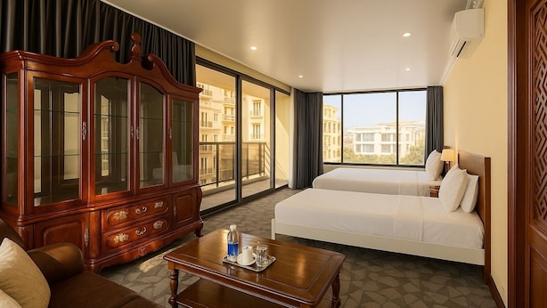 A hotel room with a large wooden cabinet, two beds, a sofa, and a coffee table. - Sam Royal Apartment (Ho Chi Minh City)