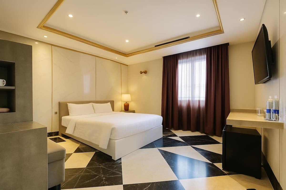A modern hotel room with a bed, a desk, a TV, and a bathroom.