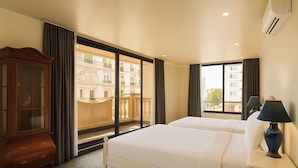 A hotel room with two beds, a wooden cabinet, and a large window offering a view of buildings. - Sam Royal Apartment (Ho Chi Minh City)