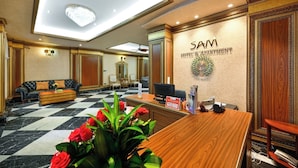 A hotel lobby with a reception desk, a sofa, a chandelier, and a check-in counter. - Sam Royal Apartment (Ho Chi Minh City)