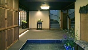 A spacious indoor area with a tiled floor, a staircase, and wooden cabinets. - Gensen no Yado Maruishi Ryokan (Hakuba)