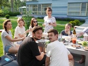 A group of people dining outdoors at a table with food and drinks. - Stockholm Studios (Irpin)