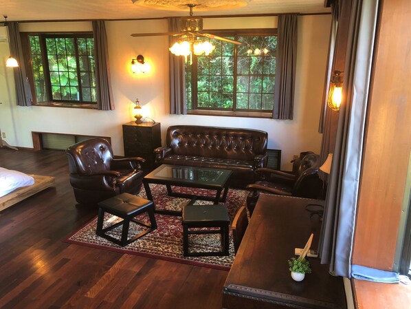 A living room with a leather sofa, glass coffee table, and wooden flooring.