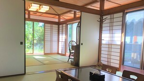 Una habitación japonesa tradicional con suelo de tatami, puertas correderas y una mesa baja con sillas.