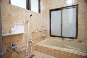 A bathroom with a bathtub, shower, and toilet. There are toiletries on a shelf. - private hotel WALKERS NAKIJIN (Nakijin)