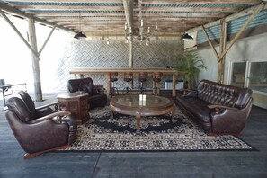 A covered outdoor seating area with leather sofas, a glass coffee table, and a patterned rug. - private hotel WALKERS NAKIJIN (Nakijin)