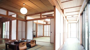 Una habitación japonesa tradicional con suelo de tatami, puertas correderas y bajo techo de madera.