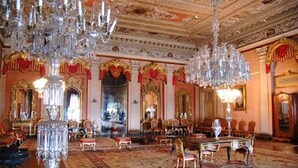 Une vaste pièce agrémentée de lustres somptueux, d’un grand miroir décoratif et d’un sol recouvert d’une moquette rouge.