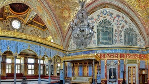 Un intérieur somptueux, agrémenté d’un lustre, de murs à motifs et d’une grande fenêtre.