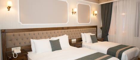 Habitación de hotel con dos camas, cabecero de madera, mesitas de noche, teléfono y lámparas de pared.
