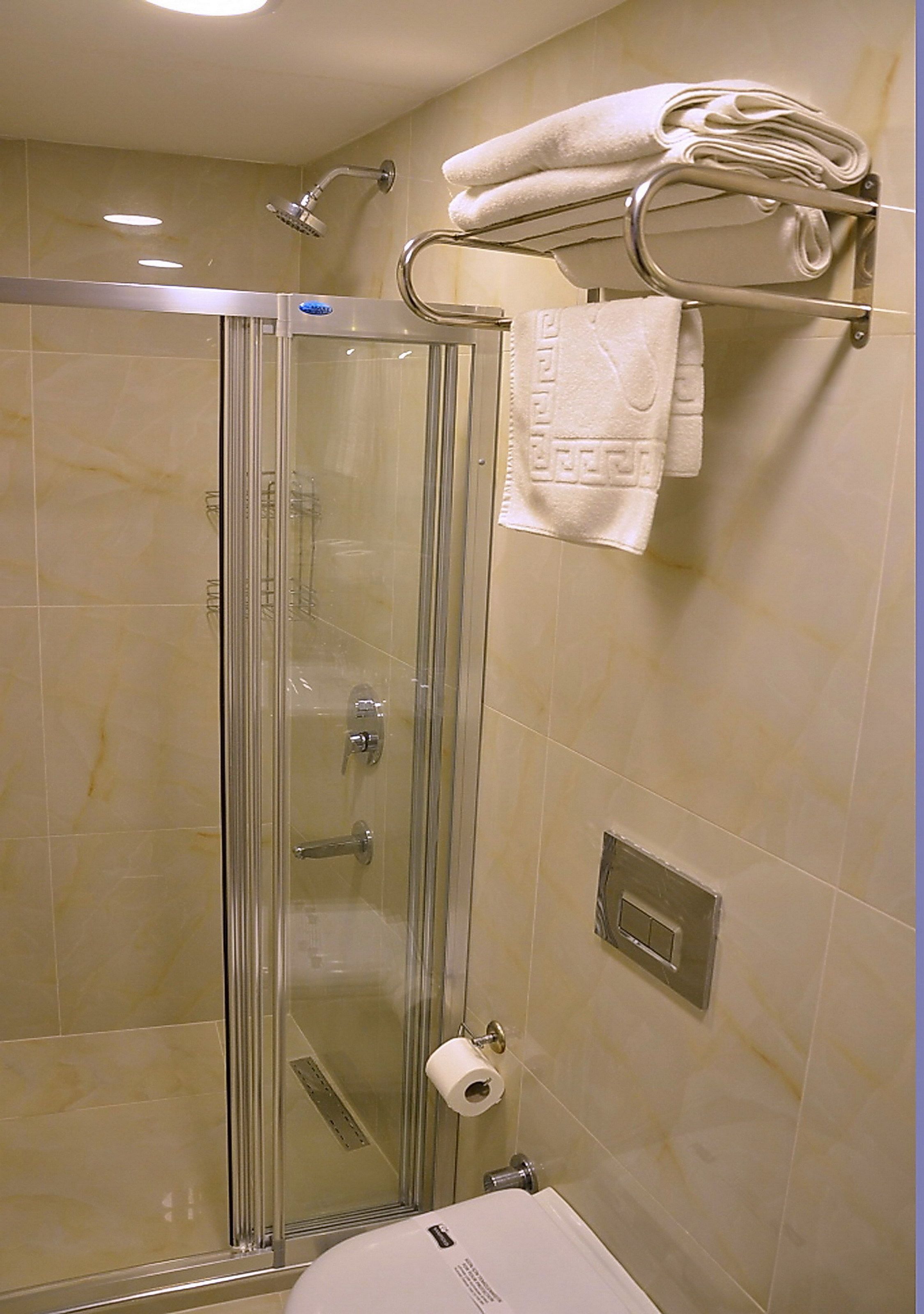A glass-enclosed shower with a towel rack above it.