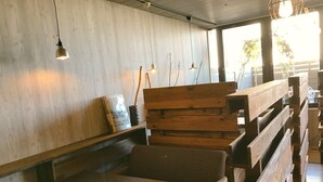 A modern interior with wooden benches and tables, pendant lighting, and a concrete wall. - Apoa Hotel Tsu (Tsu)