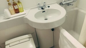 A bathroom with a white sink, toilet, and bathtub. There are three bottles of liquid soap on a shelf above the sink. - Apoa Hotel Tsu (Tsu)