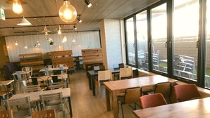 A restaurant with wooden tables and chairs, hanging pendant lights, and large windows offering a view of the outside. - Apoa Hotel Tsu (Tsu)