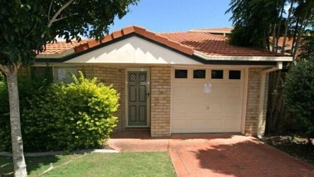 A single-story house with a beige garage door, a small attached garage, and a brick pathway leading to the entrance. - Huntington Villas (Warner)