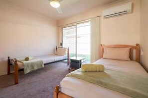 Ein Zimmer mit zwei Betten, einem kleinen Tisch und einem Fenster mit Blick.