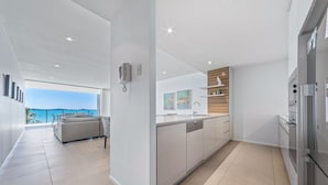Een moderne keuken met een centraal eiland, een zithoek met een bank en uitzicht op zee.