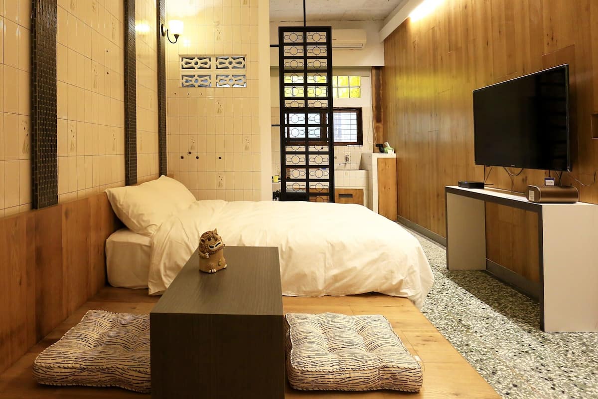A hotel room with a bed, a desk, a TV, and a decorative lion statue.