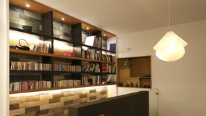Una biblioteca moderna con estanterías, un muro de piedra y una lámpara colgante.