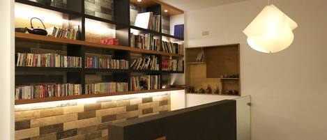 A modern library with bookshelves, a stone wall, and a hanging light fixture.