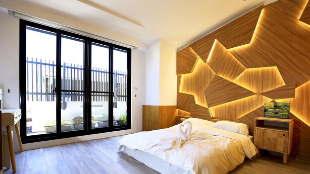 Un dormitorio moderno con un ventanal grande, cabecera de madera y cama bien tendida.