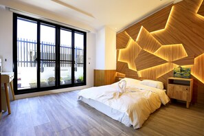 Een moderne slaapkamer met een groot raam, een houten hoofdbord en een net opgemaakt bed.